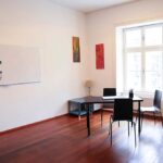 seminarraum-mieten-raum2-14 - Zentrum für Stimme & Sprechen Small meeting room: rectangular table with three black chairs, whiteboard on the wall, and a large window letting in light.